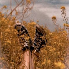 a person standing in tall grass with their feet up