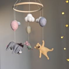 three stuffed animals hanging from a mobile in a child's room with gold lights