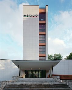 stairs lead up to the front entrance of a tall building with a mexican sign on it