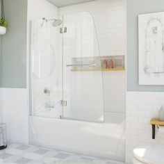 a bathroom with a white tiled floor and walls, along with a bathtub that has a glass door