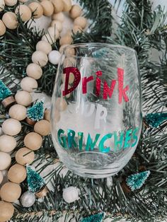 a wine glass with the words drink for gringies on it next to some christmas decorations