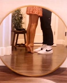 a man and woman standing in front of a mirror with their feet on the ground