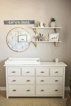 a baby's room with white dressers and shelves on the wall above it