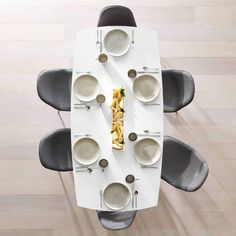 an overhead view of a dining table with plates and bowls on it, in the middle of a wood floor