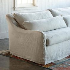 a white couch sitting on top of a rug next to a window