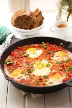 an iron skillet filled with eggs and tomato sauce on top of a white table