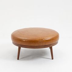 a brown leather ottoman sitting on top of a white floor