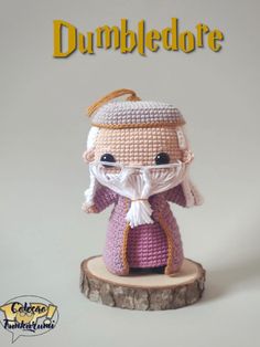 a crocheted doll is sitting on top of a tree stump with the words dumbledore written above it