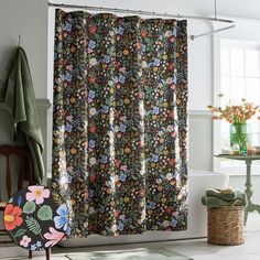 a shower curtain with flowers on it and a chair in the corner next to it