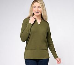 a woman is smiling and posing for the camera while wearing a green sweater with an open v - neck