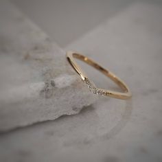 a gold wedding band with small diamonds on top of a white marble slabd surface