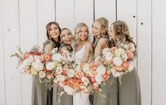 a group of women standing next to each other in front of a white wooden wall