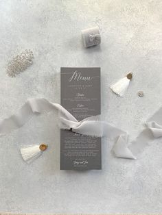 a menu card with tassels on it and some other items scattered around the table