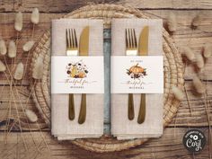 two gold forks and napkins sitting on top of a wooden table next to each other