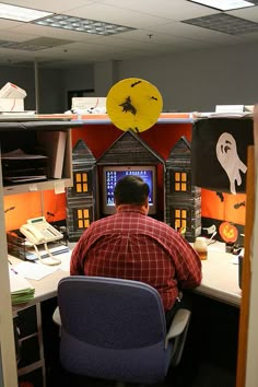 a man sitting at a desk in front of a computer monitor with halloween decorations on it