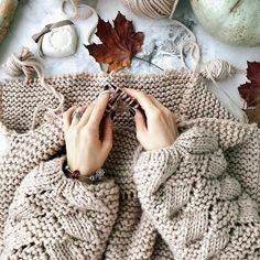 a woman is knitting in her knitted sweater surrounded by autumn leaves and yarn balls