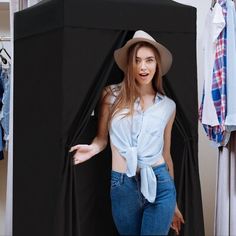 a woman standing in front of a black box with her hands out and wearing a hat