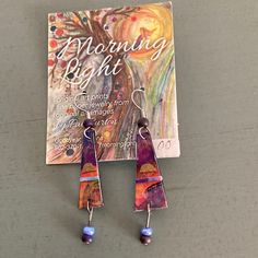 a pair of earrings sitting on top of a table next to a book with an image of a tree