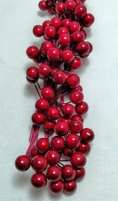 some red berries are laying on a white surface and ready to be used as decorations