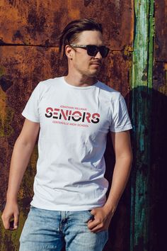 a man standing in front of a rusted wall wearing a white t - shirt