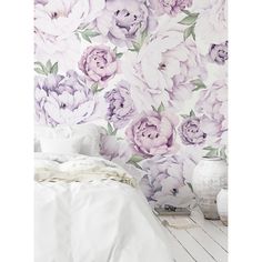 a white bed sitting next to a purple flower wallpaper