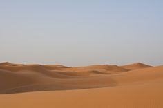 an empty desert with sand dunes in the distance