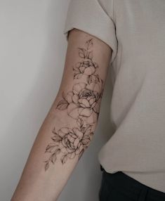 a woman's arm with flowers on it and a black ink tattoo that has been drawn