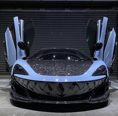 a blue and black sports car with its doors open