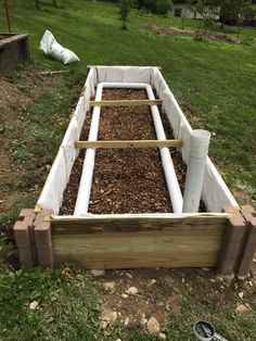 a raised garden bed in the middle of a yard with wood and mulch around it