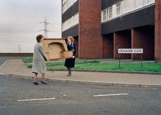 two women are walking down the street with an open box in their hands and one woman is carrying it