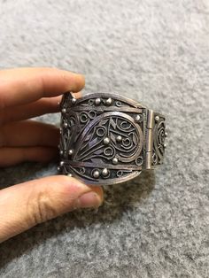 A beautiful antique Algerian silver bracelet with Morocco silver marks, silver filigree, with a sliding pin closure. Handmade from 80 percent silver. The filigree is in good condition and the bracelet functions as it should. It is in general in good vintage condition. Width of large side : 5cm Width of small side : 2,8 cm Inner diameter : 5,9cm Weight : 67,9g Ornate Antique Silver Carved Jewelry, Silver Carved Bracelet, Ornate Engraved Cuff Bracelet, Traditional Adjustable Filigree Bracelets, Ceremonial Silver Filigree Bangle, Adjustable Traditional Filigree Bracelets, Ornate Handmade Antique Silver Bracelet, Victorian Silver Bangle With Intricate Design, Carved Silver Bracelet