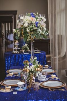 a table set with blue sequins and gold place settings for an elegant dinner