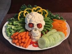 a white plate topped with vegetables and a skull made out of cauliflower, carrots