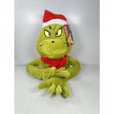 a green stuffed animal with a red scarf and santa hat on it's head