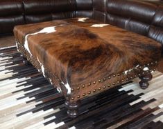 a brown and white cowhide ottoman on top of a rug