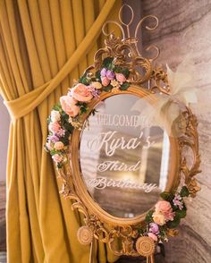 a mirror that is sitting on top of a table next to a window with yellow drapes