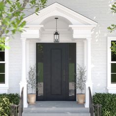 a white house with black front door and two planters