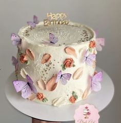 a birthday cake decorated with butterflies and the words happy birthday written on top is sitting on a white plate