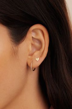 a close up of a woman's ear wearing an earring with two hearts on it