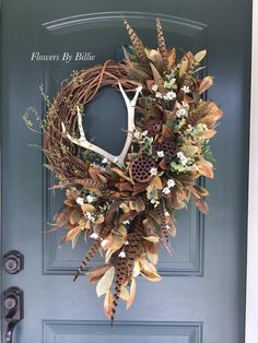 a wreath with deer antlers and flowers on the front door