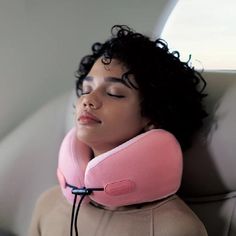 a woman laying down with a pink pillow on her head and earphones around her neck