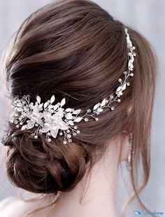 a woman wearing a bridal headpiece with flowers and leaves on it's side