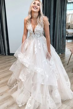 a woman in a white wedding dress standing on a wooden floor with her eyes closed