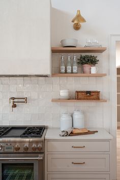 a stove top oven sitting inside of a kitchen next to a wooden shelf filled with dishes