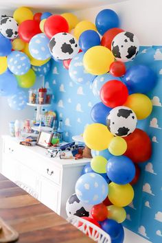 a bunch of balloons that are in the shape of a cow on a blue wall