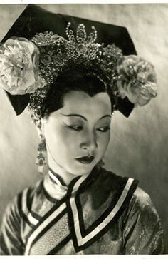 an old black and white photo of a woman wearing a hat with flowers on it