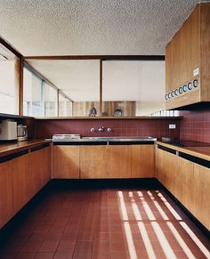 an empty kitchen with wooden cabinets and tile flooring is pictured in this image, the sun shines through the windows