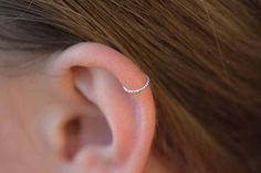 a woman's ear with a single diamond in the middle