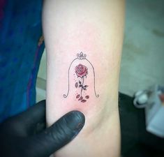 a small tattoo on the arm of a person with a rose in a glass dome