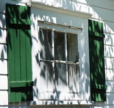 an old window with green shutters on a white house